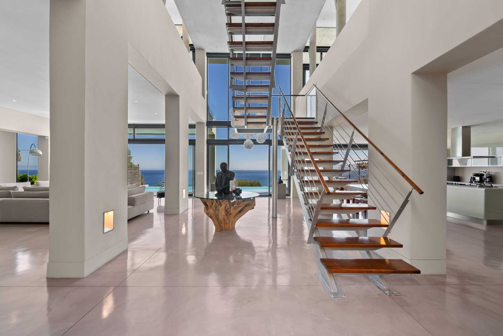 Open-plan double-height interior of a Camps Bay home, with sculptural staircase and ocean view